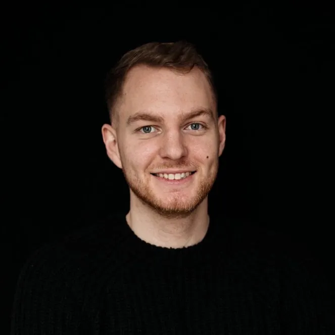 Portrait of Julian smiling in front of a black background