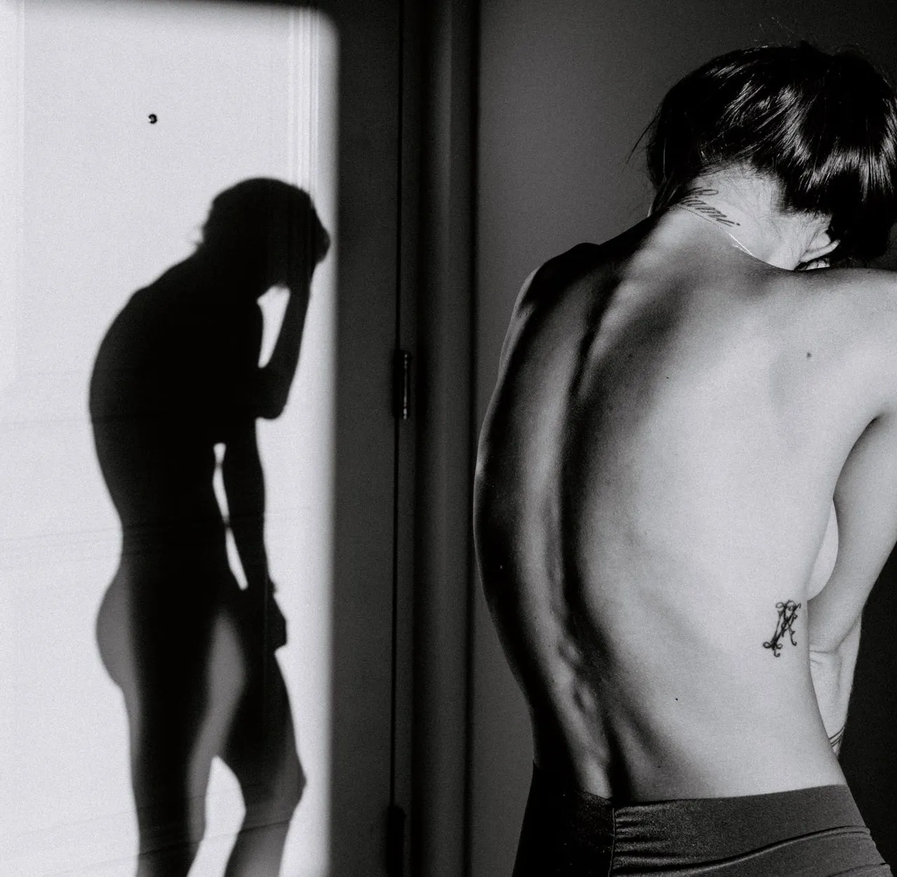 The back of a woman hugging herself and the shadow of a muscular man