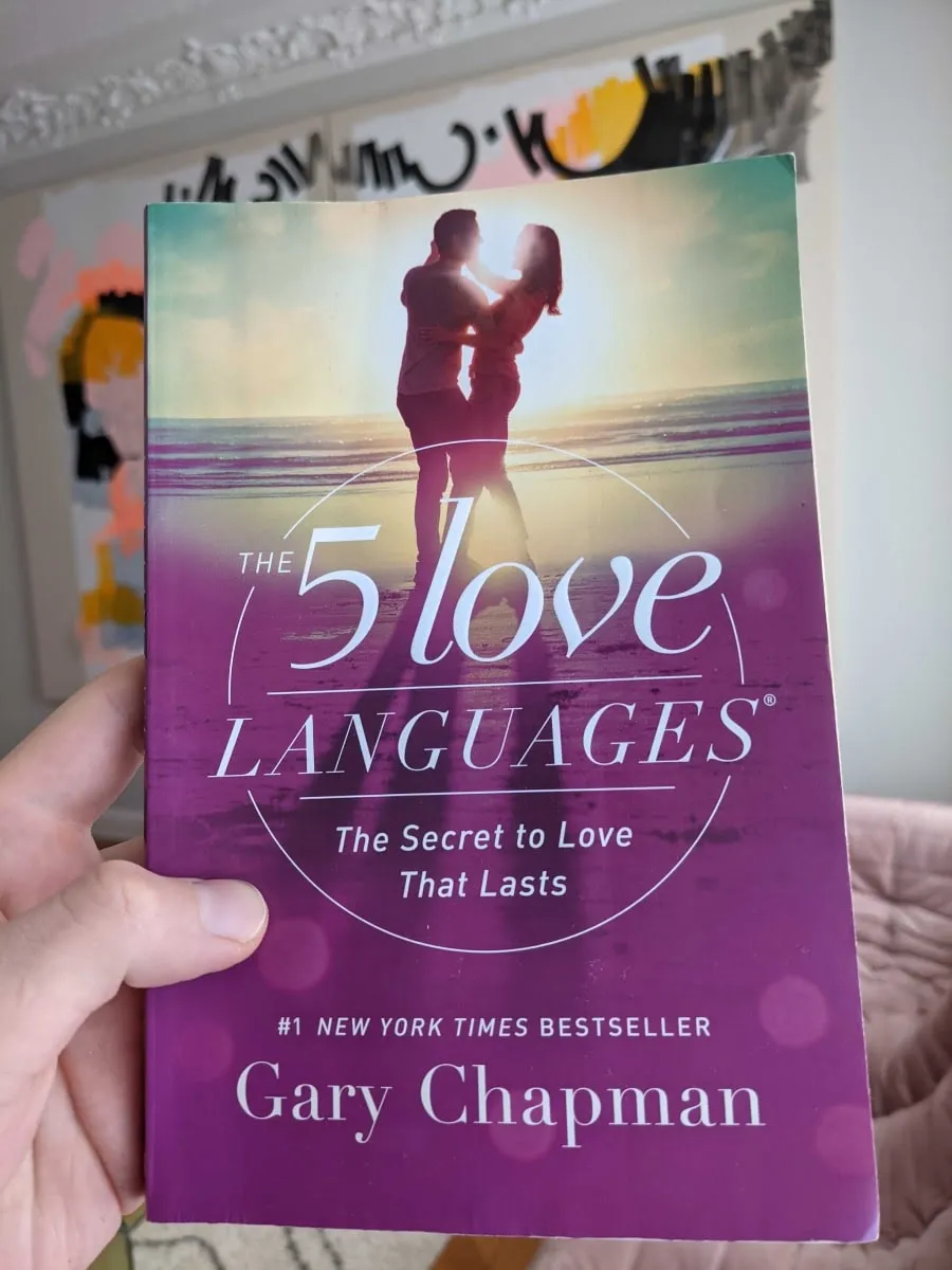A hand holding the book "The 5 Love Langauges" by Gary Chapman