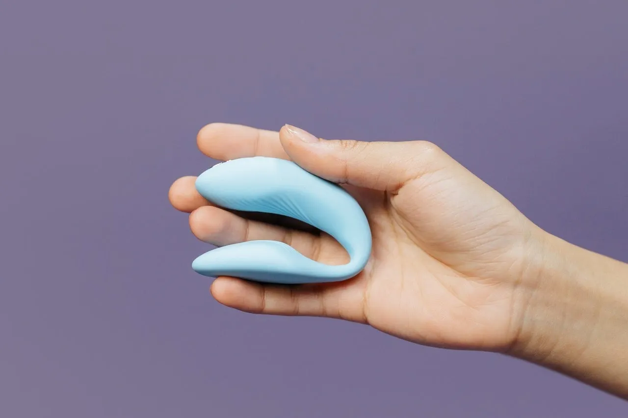 A hand holding a blue couple vibrator