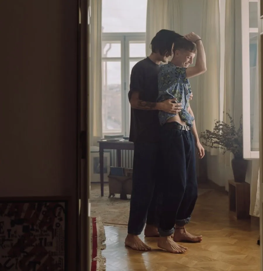 A man hugging a woman from behind inside a flat